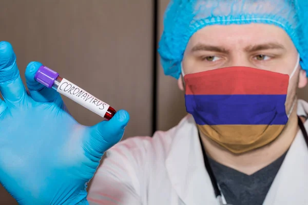 Doctor wearing mask with flag Armenia holding a blood test for the Coronavirus
