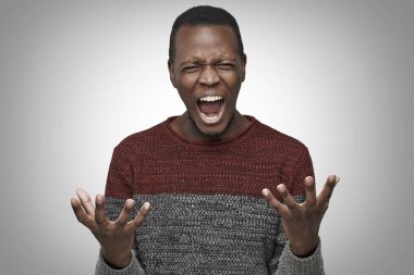Kapa çeneni kavramı. Elleriyle el hareketi ile ağız açık, bağırarak deli esmer adam. Bağırıyor, çılgın ve öfke dolu arıyor kızgın ve tahriş olmuş genç Afro-Amerikan erkek portresi stüdyo