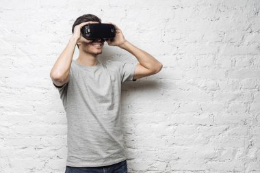 Teknoloji, bilim, yenilik ve siber kavramı. Vr giyen genç çekici beyaz erkek portresi gözlükler. Beyaz adam beyaz duvara karşı 3D kulaklık kullanarak sanal gerçeklik yaşıyor