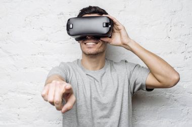 Sanki bir şey ile etkileşim onun parmakları işaret 3d gözlük, yakışıklı Beyaz delikanlı. Çekici adam Vr kulaklık kullanarak video oyunu oynarken sanal gerçeklik yaşandığı gülümseyen