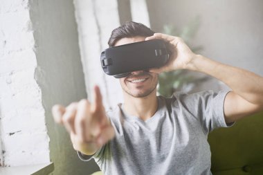 Portre sanal gerçeklik gözlükleri modern coworking Studio giyen bir şeyle, etkileşim sanki parmak ile işaret Avrupa çekici bir adam portresi. Gelecek şu andır. VR teknolojisi kullanarak