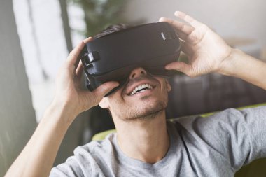 Portait eğlence için yuvarlak pencere yarığı Kulaklık kullanırken sanal gerçeklik karşılaşan insanın yakın stüdyo coworking oturuyor. Yakışıklı adam yeni bir gerçeklik, zevk Vr giymiş headshot koruyucu gözlük