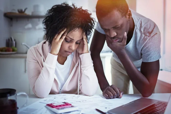 Joven pareja afroamericana estresada en problemas, no tienen dinero para pagar deudas, para pagar el alquiler de un apartamento. Esposa sosteniendo la cabeza en la desesperación, no puede pagar las facturas, tener problemas financieros. Presupuesto familiar —  Fotos de Stock