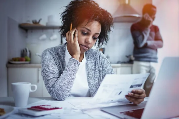 Pareja afroamericana joven que enfrenta problemas financieros y no es capaz de pagar deudas. Mujer desesperada agarrada de la mano en su mejilla, sintiéndose estresada mientras maneja el presupuesto familiar en la mesa de la cocina —  Fotos de Stock