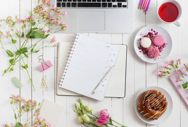 Feminino flat lay espaço de trabalho com laptop, xícara de chá, macarons e flores em mesa de madeira branca. Vista superior mock up . — Fotografia de Stock