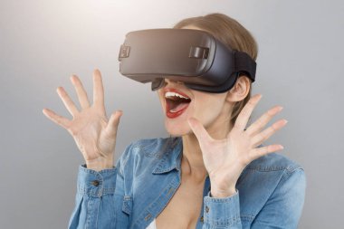 Çekici kadın kesinlikle sanal gerçeklik deneyimi tarafından absorbe gri arka plan üzerinde izole sürpriz vizyonları ile mutlu ve germe parmaklarda duygu yeni dünyalar keşfetmek kapalı atış.