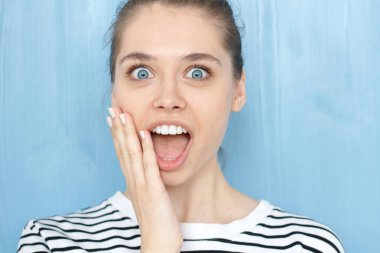 Şaşırmış gibi genç beyaz kadın çalışan veya raslantı, giyinmiş müşteri ile şok ya da sürpriz, tam güvensizlik, bağırarak portresi olan mavi backrgound karşı duran bir şey hayret