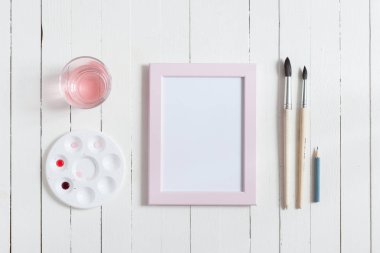 Kadar alay et. Beyaz ahşap masa üzerinde sanatçı çalışma alanı: kırmızı sulu boya, Boya fırçaları ve su