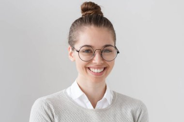 Gri arka plan rahat gösterilen trendy yuvarlak gözlük takıyor ve dostça dişlek gülümseme, iletişim ve fikirleri paylaşmak isteyen izole güzel pozitif Koleji Öğrenci kız fotoğrafı.