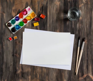 Kadar alay et. Yaratıcı alan. Koyu ahşap masa sanatsal çalışma araçları: sulu boya, Boya fırçaları ve su.