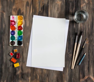 Kadar alay et. Yaratıcı alan. Koyu ahşap masa sanatsal çalışma araçları: sulu boya, Boya fırçaları ve su.