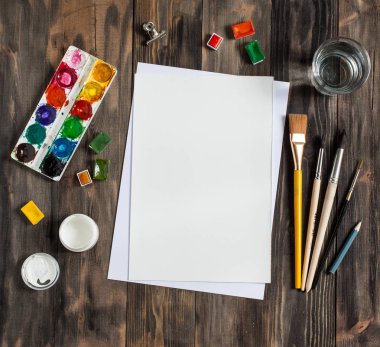 Kadar alay et. Yaratıcı alan. Koyu ahşap masa sanatsal çalışma araçları: sulu boya, Boya fırçaları ve su.