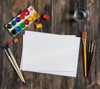 Kadar alay et. Yaratıcı alan. Koyu ahşap masa sanatsal çalışma araçları: sulu boya, Boya fırçaları ve su.