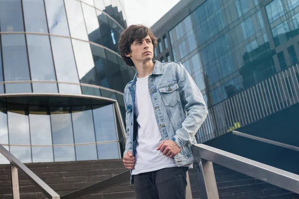 Kot ceket ayakta merdivenlerde şehir arka plan karşı giyen bir düşünceli yakışıklı genç portresi