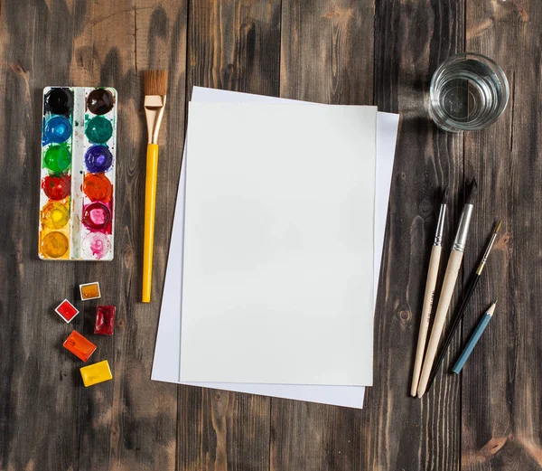 Kadar alay et. Yaratıcı alan. Koyu ahşap masa sanatsal çalışma araçları: sulu boya, Boya fırçaları ve su.