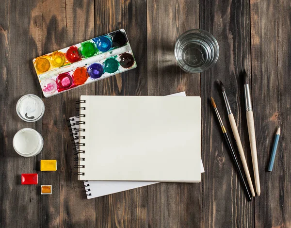Kadar alay et. Yaratıcı alan. Koyu ahşap masa sanatsal çalışma araçları: sulu boya, Boya fırçaları ve su