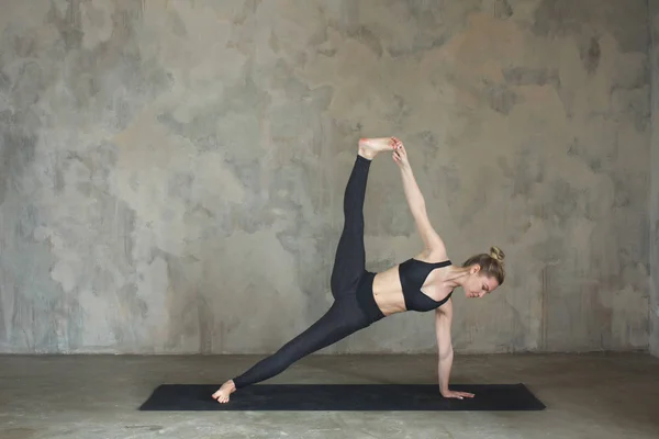 Mujer joven practicando yoga Posada de tablón lateral, Vasisthasana avanzó contra pared texturizada / fondo urbano — Foto de Stock