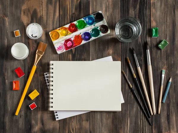 Kadar alay et. Yaratıcı alan. Koyu ahşap masa sanatsal çalışma araçları: sulu boya, Boya fırçaları ve su