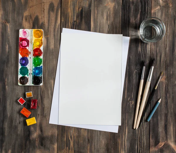 Kadar alay et. Yaratıcı alan. Koyu ahşap masa sanatsal çalışma araçları: sulu boya, Boya fırçaları ve su.