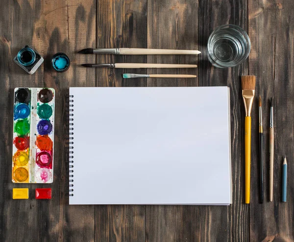 Kadar alay et. Yaratıcı alan. Koyu ahşap masa sanatsal çalışma araçları: sulu boya, Boya fırçaları ve su
