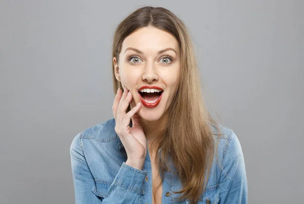 Photo of young European lady isolated on grey background extremely surprised with mouth and eyes open wide. Copyspace, concept of favorable commercial offer, discounts, sale or positive changes.