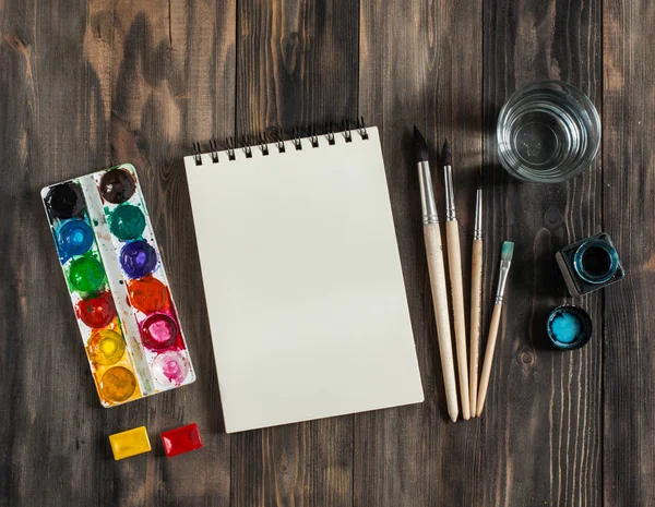 Kadar alay et. Yaratıcı alan. Koyu ahşap masa sanatsal çalışma araçları: sulu boya, Boya fırçaları ve su