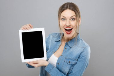 Güzel moda duygusal Avrupa Bayan boş tablet geniş mutlu sürpriz gülümseme ile sunulması gri arka plan üzerinde izole kapalı closeup. Boşaltmak için reklam mal ve hizmet.