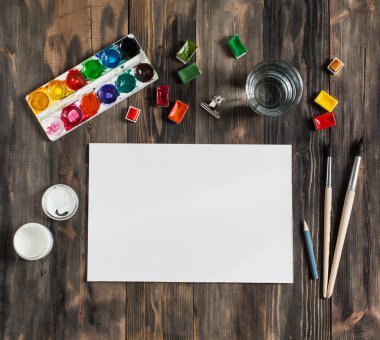 Kadar alay et. Yaratıcı alan. Koyu ahşap masa sanatsal çalışma araçları: sulu boya, Boya fırçaları ve su.