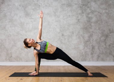 Genç kadın pratik yoga Bikram üçgen, Trikonasana tekstüre duvara / kentsel poz arka plan 