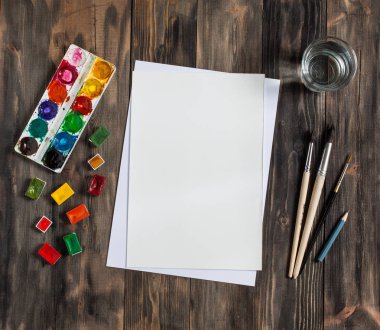 Kadar alay et. Yaratıcı alan. Koyu ahşap masa sanatsal çalışma araçları: sulu boya, Boya fırçaları ve su.