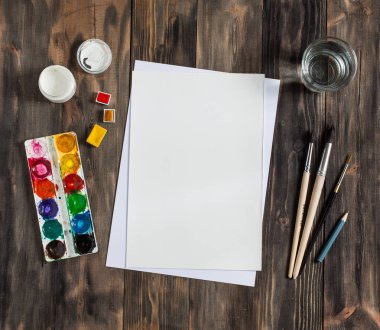 Kadar alay et. Yaratıcı alan. Koyu ahşap masa sanatsal çalışma araçları: sulu boya, Boya fırçaları ve su.