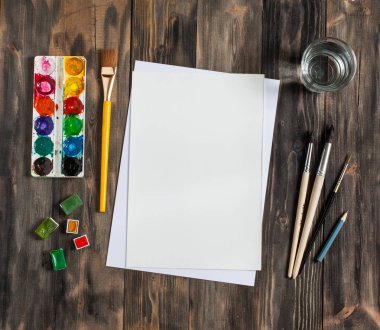 Kadar alay et. Yaratıcı alan. Koyu ahşap masa sanatsal çalışma araçları: sulu boya, Boya fırçaları ve su.