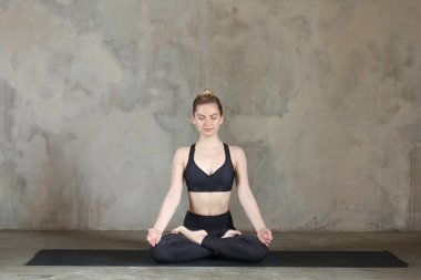 Genç kadın Lotus poz pratik / padmasana tekstüre duvara / kentsel arka plan 