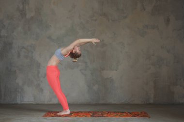 Genç kadın hasta Uttanasana, silah kaldırdı yoga poz tekstüre duvara / kentsel pratik arka plan 
