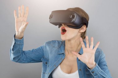 Çekici kadın keşfetmek ve sanal gerçeklik fırsatları keşfetmek gri arka plan üzerinde izole bir kadeh. Vizyonları bu yüzden sadık eller ileriye uzanan nesneleri dokunmaya kalkarsa hayat vardır.