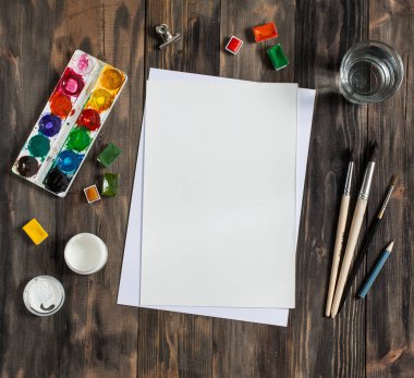 Kadar alay et. Yaratıcı alan. Koyu ahşap masa sanatsal çalışma araçları: sulu boya, Boya fırçaları ve su.