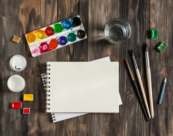 Kadar alay et. Yaratıcı alan. Koyu ahşap masa sanatsal çalışma araçları: sulu boya, Boya fırçaları ve su