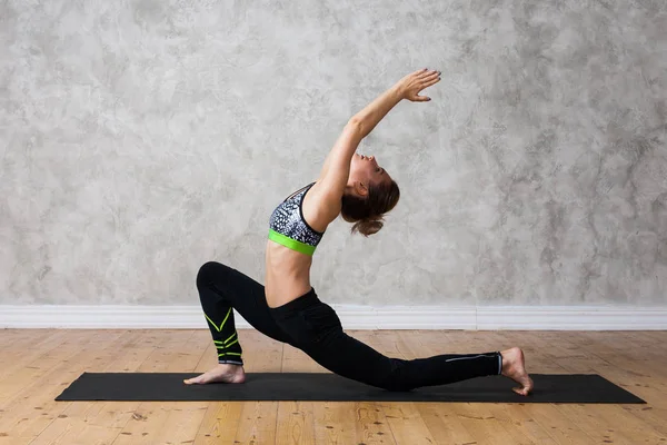 Jovem praticando ioga Baixa postura lunge, Urdhva Ashva Sanchalasana contra parede texturizada / fundo urbano — Fotografia de Stock