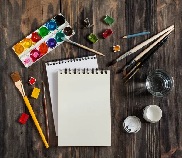 Kadar alay et. Yaratıcı alan. Koyu ahşap masa sanatsal çalışma araçları: sulu boya, Boya fırçaları ve su