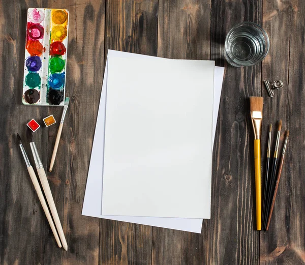 Kadar alay et. Yaratıcı alan. Koyu ahşap masa sanatsal çalışma araçları: sulu boya, Boya fırçaları ve su.
