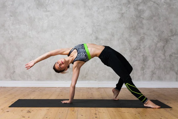 Mujer joven practicando yoga Wild Thing Pose, Camatkarasana contra pared texturizada / fondo urbano — Foto de Stock