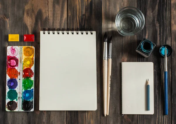 Kadar alay et. Yaratıcı alan. Koyu ahşap masa sanatsal çalışma araçları: sulu boya, Boya fırçaları ve su