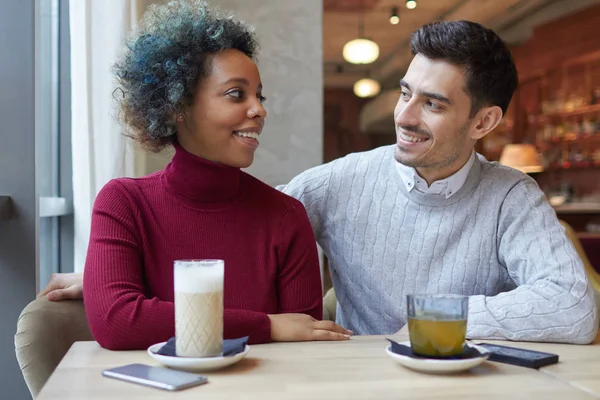 Portrait d'amoureux heureux passant leur déjeuner ensemble dans un petit café, profitant de leur rendez-vous, café et thé, ayant laissé des téléphones allongés sur la table, souriant et se regardant dans les yeux avec un amour profond . — Photo