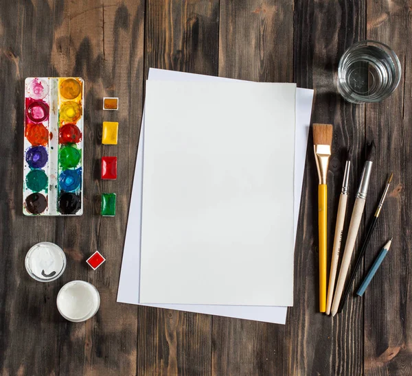 Kadar alay et. Yaratıcı alan. Koyu ahşap masa sanatsal çalışma araçları: sulu boya, Boya fırçaları ve su.