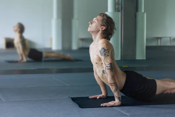 Handsome tattooed man practicing yoga. Close up shot of young m