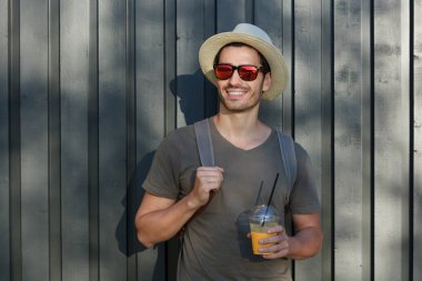 Yatay görüntü yakışıklı beyaz adam rahat kıyafetler ve ilginç yerler keşfetmek güneş gözlüğü ile sağa doğru seyir şapka giyen kırsal ortamda resimde üzerinde gri ahşap arka plan