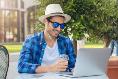 Tarama ve müzik veya video çağrısı mutlu dostu gülümseme ile cevap kontrol sosyal ağlar üzerinden dizüstü bilgisayar, süre kafeterya masada boş vaktinizi olumlu Avrupa adam açık fotoğraf