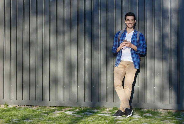 Cep telefonu elinde tutan sokak gösterimler ya da fotoğraf çekmek için hevesli bir ilgi ile izlerken olsa arkasında gri ahşap arka plan ile genç yakışıklı beyaz erkek tam yükseklikte görüntü resim