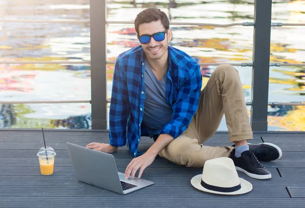 Genç açık görüntü raslantı Avrupa erkek zevk boş zaman arkasında, sohbet veya web sayfaları, tarama Gölü manzaralı gri ahşap köprü kameraya bakarak geçiriyor giyinmiş