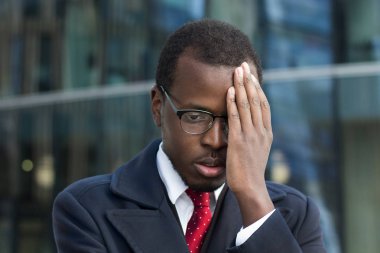 Son derece sorunlu seyir gökdelenler ile çevrili sokakta resimde genç Afro-Amerikalı işadamı kentsel closeup şaşkın ve o yüzleri sorunla başa çıkmak nasıl bilmeden yorgun